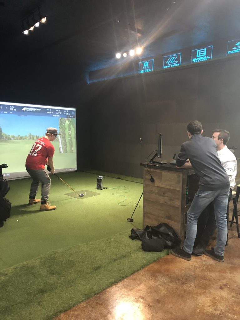 A group of people inside the indoor golfing facility