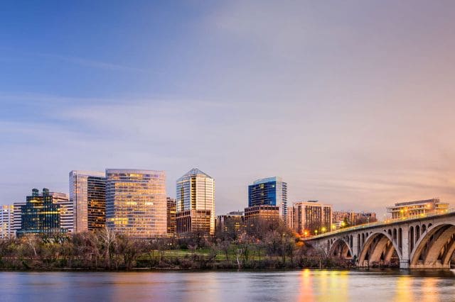 Skyline of modern buildings near a river at dusk, with a large bridge on the right and a clear sky above, reminiscent of the precision found in SwingFit’s golf club fitting process.