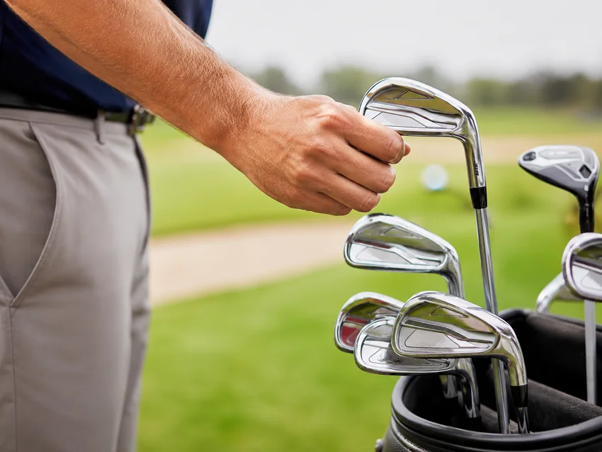 Golfer selecting an iron from a golf bag
