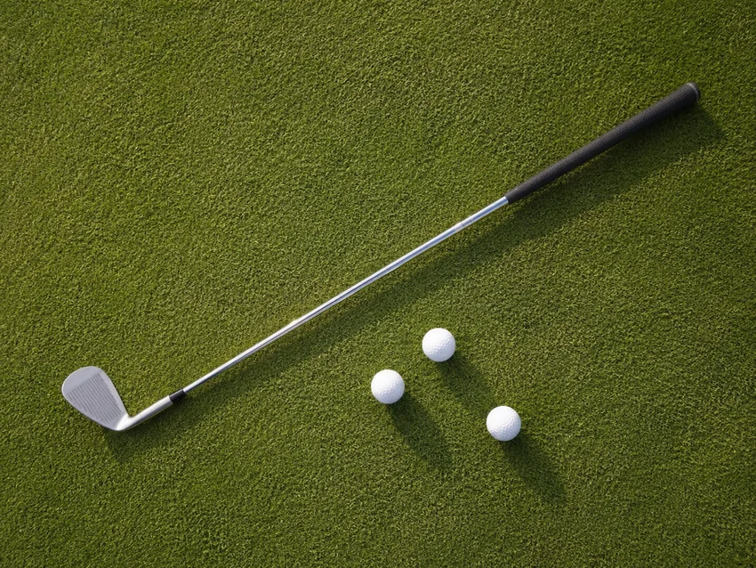 Golf iron and practice balls on grass