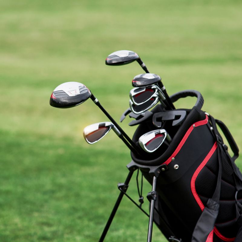 A golf bag with multiple clubs stands on a grassy golf course.